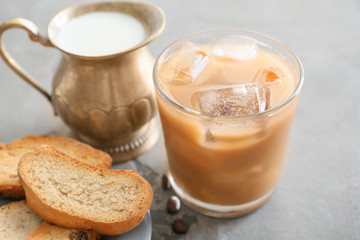 Glass of tasty iced coffee with cookies on grey background