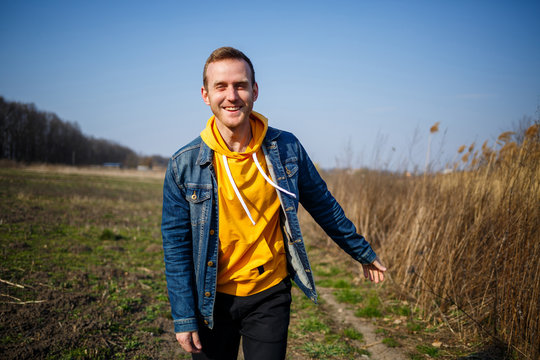 Smiling man enjoying wind blowing in forest. Happy man feeling joy while walking at nature, free space on green trees background. Life love, joy, fresh air, renovation concept