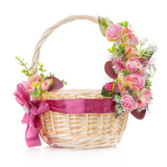 Fototapeta na wymiar Wicker basket with delicate pastel decor. Pink flowers and ribbon with bow. Isolated on a white background
