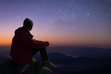 Silhouette of young traveler sitting and watched the star and milky way on the Himalayas mountain...