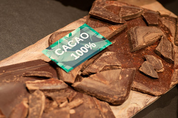 Raw cocoa beans, clay bowl with cocoa powder, chocolate, ounces of chocolate
