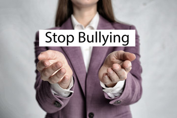 Young woman showing sign STOP BULLYING on light background, closeup