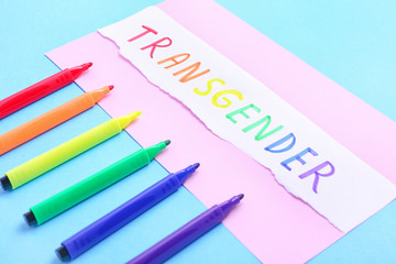 Paper with word TRANSGENDER and markers on color background