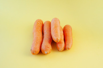 fresh orange unshelled large carrots on a yellow background