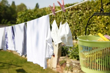 drying white clothing. washing, drying, cleaning of reusable cotton medical surgical mask for protection of coronavirus infection COVID-19. dried on clothesline in open air and sunlight for reuseable