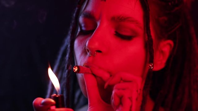 smokes marijuana close-up, a girl with dreadlocks in red and blue, a freak for the legalization of marijuana, a ganja