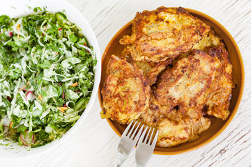 Turkey fillet in batter in a ceramic bowl, and big bowl with green salad