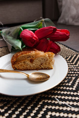 a bouquet of red tulips with a slice of a holiday cake on a plate