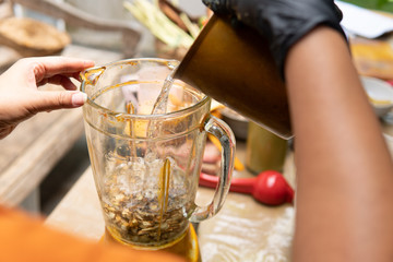 hand gesture pure water to ingredient in blender for traditional herbal drink