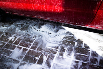 hand washing a red car with foam