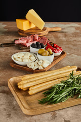High angle view of antipasto ingredients on boards on brown surface isolated on black