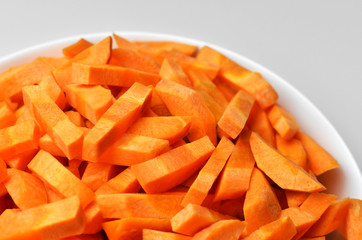 Chopped carrot in white bowl. Vegan food background. Carrot sticks. Food preparation.