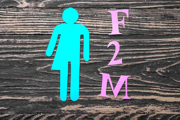 Transgender figure and abbreviation F2M on wooden background