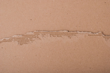 Old textured cardboard sheet with torn edges. Brown cardboard torn off. Cardboard texture. A sheet of tattered cardboard lies on a whole sheet of cardboard