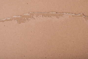 Old textured cardboard sheet with torn edges. Brown cardboard torn off. Cardboard texture. A sheet of tattered cardboard lies on a whole sheet of cardboard