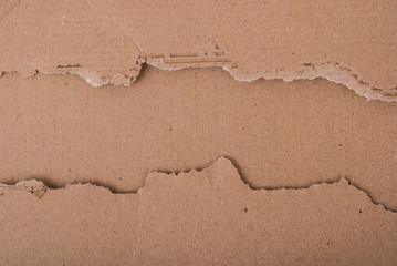 Old textured cardboard sheet with torn edges. Brown cardboard torn off. Cardboard texture. A sheet of tattered cardboard lies on a whole sheet of cardboard