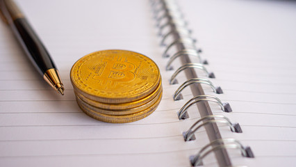 Bitcoin coin  and pen placed on blank book, have copy space, Concept Investors will accumulate gold or digital money