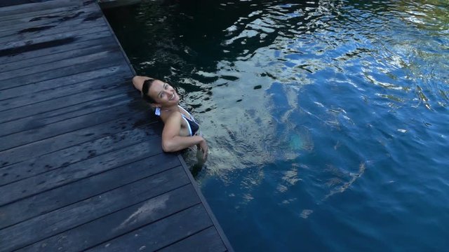 Portrait of, pretty, happy woman relaxing in pool, super slow motion 240fps