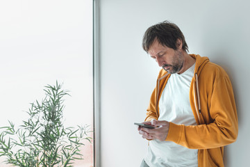 Man with yellow zip hoodie using mobile phone in morning