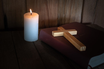 The crucifix lay on the bible. While there are candles that are illuminating Christian religious...