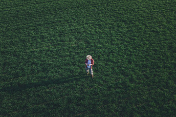 Wheat farmer using drone remote controller in wheatgrass field, aerial