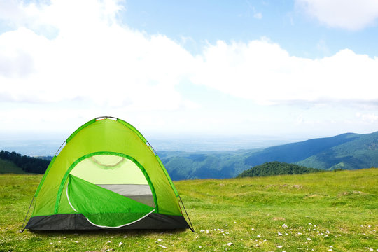 Green camping tent in mountains on sunny day