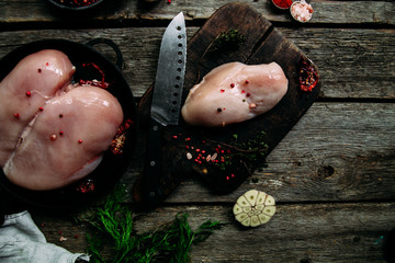 Uncooked Chicken fillet on a wooden table with spices