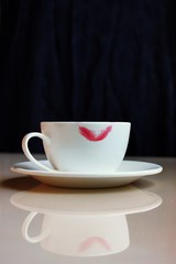 A cup of hot tea with a lipstick print is on the table