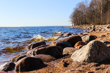 Rocky beach by the sea. Beautiful landscape. Bay, blue sky, rocks, sand. Waves on clean and clear water in sunny day. Travel concept. Nature concept. Wonderland summer background.   