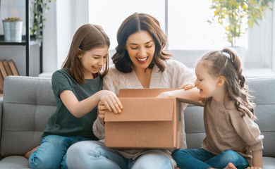 Mother and daughters are unpacking cardboard