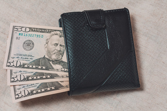 Black wallet with dollars 50 on a gray background.