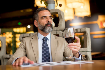 Handsome mature man drinking glass of red wine in restaurant