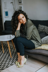 Beautiful young woman sitting by the table in the room