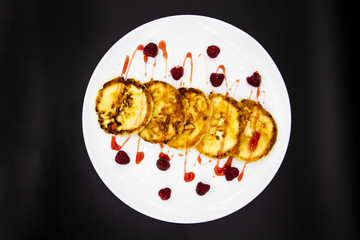 Ukrainian cottage cheese fritters, syrniki with jam on white plate. Cheese pancakes with raspberry without GMO. Delicious breakfast food at the morning.
