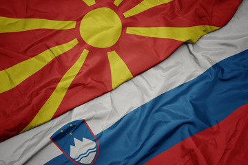 waving colorful flag of slovenia and national flag of macedonia.