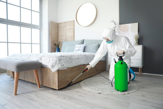 Worker In Biohazard Suit Disinfecting House