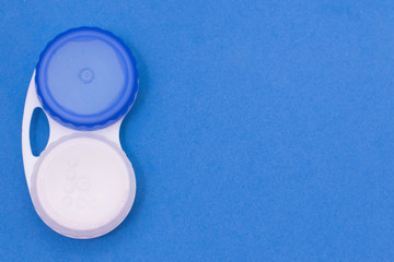 Contact lens container on a blue background. Storage o cleaning contact lenses for vision correction, place for text, copy space