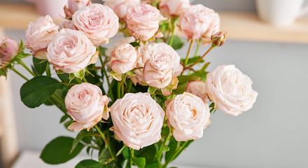 Utensils, bouquet of roses and mugs on shelf. Dishes in cupboard in kitchen.