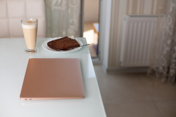 Closed laptop with a glass of coffee and chocolate pie