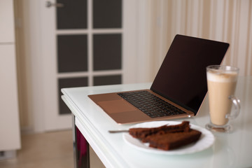 Laptop with a glass of coffee and homemade chocolate cake