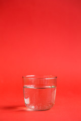 Transparent glass of water on a red background