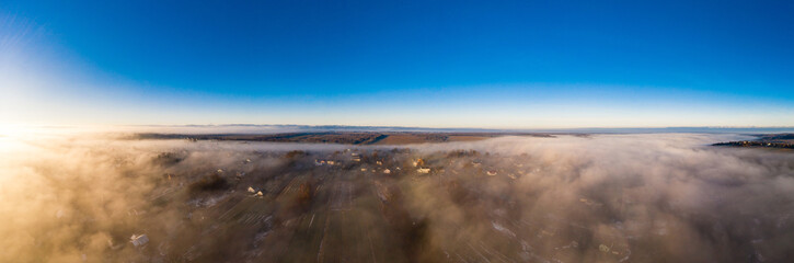 Beautiful panorama of winter village covered with dense fog from aerial view
