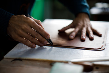 Fototapeta na wymiar A leather craftsman works in a workshop. 