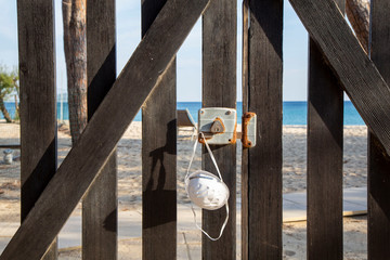 Protective mask on the wooden fence. Closed beach due to Coronavirus (Covid19) quarantine. Campo nell'Elba, Italy