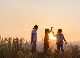 Silhouette of children playing on mountain at sunset background