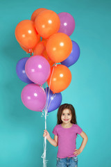 Fototapeta na wymiar Smiling little child girl in pink t-shirt posing with bright colorful air balloons isolated on blue background. birthday party.