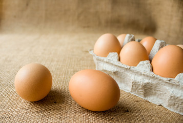 Close-up of fresh raw organic chicken eggs in egg box on natural fabric background from local farmer market with copyspace. Selective focus