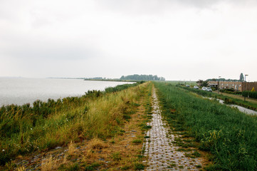 Rainy weather on the sea, where the coastline with green grass is visible