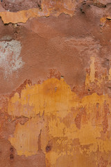 The plaster on the wall, painted in yellow color. Peeling paint. Design background or copy space