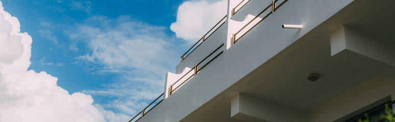 panoramic shot of modern building against blue sky with white clouds